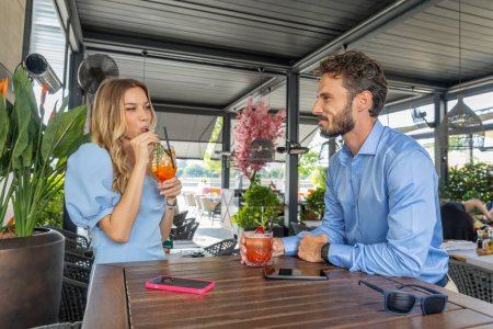 Photo for Couple drinking cocktails in outdoor restaurant garden - Royalty Free Image