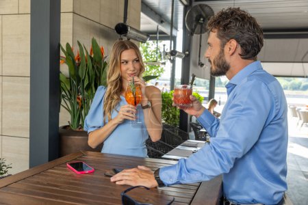 Photo for An attractive young woman flirting with a man at an outdoor cocktail bar - Royalty Free Image