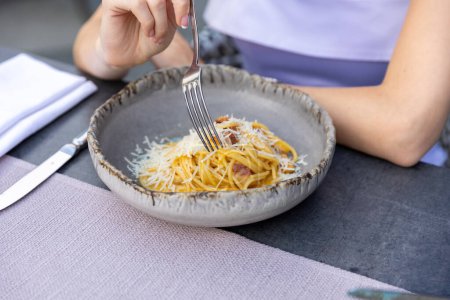 Foto de Pasta carbonara servida en un plato en una mesa de restaurante - Imagen libre de derechos