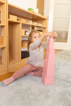 Téléchargez les photos : Petite fille jouant avec des cubes en bois à la maternelle - en image libre de droit
