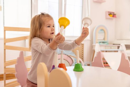 Téléchargez les photos : Petite fille jouant avec des cloches à la maternelle - en image libre de droit
