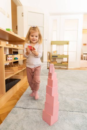 Photo for Small girl playing with wooden cubes in the kindergarten - Royalty Free Image