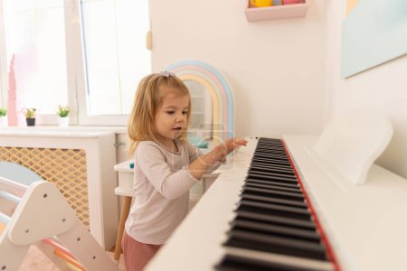 Téléchargez les photos : Little girl playing a piano - en image libre de droit