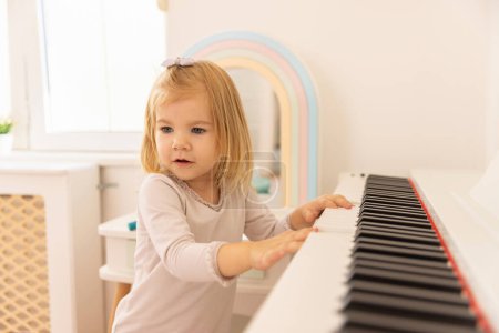 Téléchargez les photos : Little girl playing a piano - en image libre de droit