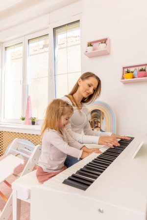 Téléchargez les photos : Petite fille jouant du piano avec sa mère - en image libre de droit