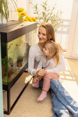 Téléchargez les photos : Petite fille regardant des poissons dans un aquarium avec sa mère - en image libre de droit