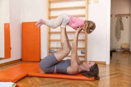 Téléchargez les photos : Jeune femme avec un enfant faisant de l'exercice en classe de gym pour perdre du poids de bébé - en image libre de droit
