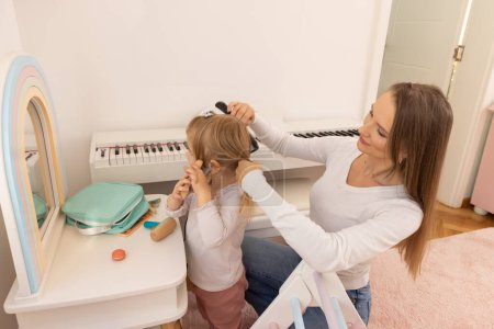 Téléchargez les photos : Mère coiffe les cheveux de sa fille - en image libre de droit