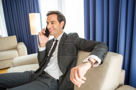 Téléchargez les photos : Homme d'affaires parlant sur le téléphone portable dans sa chambre d'hôtel - en image libre de droit