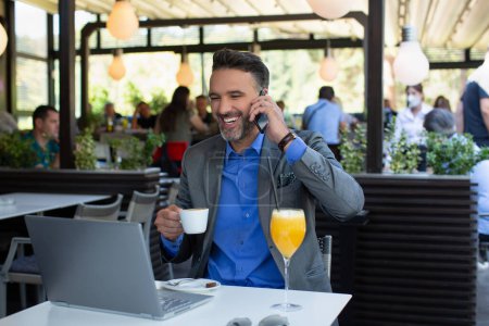 Téléchargez les photos : Homme d'affaires heureux en costume parler sur le smartphone et rire dans le restaurant - en image libre de droit