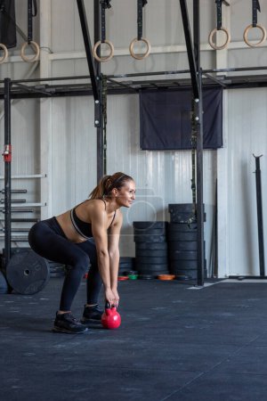 Téléchargez les photos : Femme faisant des exercices de kettlebell dans la salle de gym - en image libre de droit