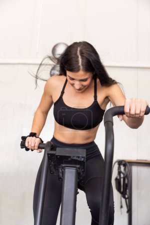 Téléchargez les photos : Femme ayant un entraînement intensif élevé sur un vélo dans la salle de gym - en image libre de droit
