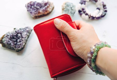 Foto de Close up view of woman hand holding red money wallet, it is believed to be bad color for wallet according to Feng Shui, so called wastes and burns money. - Imagen libre de derechos