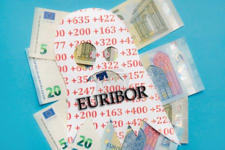 Foto de Imagen conceptual de Euribor como un monstruo aterrador flotando por encima de los billetes de banco de dinero en euros sobre fondo azul del estudio. - Imagen libre de derechos