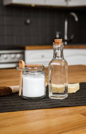 Using baking soda Sodium bicarbonate and white vinegar for home kitchen cleaning concept. White vinegar in glass bottle and baking soda in glass jar.