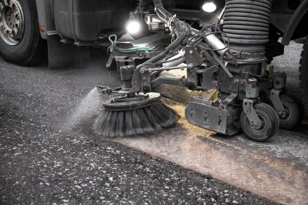 Close up view of heavy duty street cleaning vacuum machine known as street sweeper brushing the streets clean.