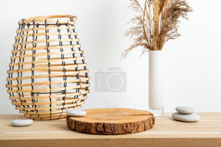 Photo for Minimal natural wood home decor with pine wood disc pedestal with bark, dry reed in vase and round wood lantern with candle burning, white wall for background. Home interior background. - Royalty Free Image