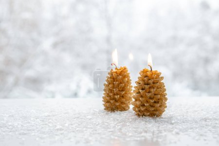 Téléchargez les photos : Bougies en forme d'épinette brûlant sur fond blanc enneigé avec paysage hivernal. Beaucoup d'espace pour copier. Hiver et Noël produits fond. - en image libre de droit