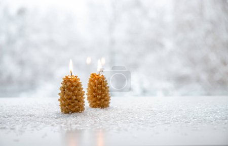 Téléchargez les photos : Bougies en forme d'épinette brûlant sur fond blanc enneigé avec paysage hivernal. Beaucoup d'espace pour copier. Hiver et Noël produits fond. - en image libre de droit
