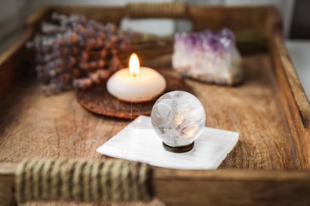 Photo for Gemstone sphere or crystal balls known as crystallum orbis and orbuculum which is the beacon of peace and harmony in home environment. Natural clear quartz ball on stand on wood tray in home. - Royalty Free Image