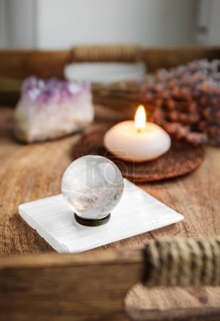 Photo for Gemstone sphere or crystal balls known as crystallum orbis and orbuculum which is the beacon of peace and harmony in home environment. Natural clear quartz ball on stand on wood tray in home. - Royalty Free Image