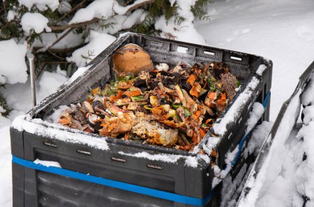 Offene Komposttonne mit Biomüll drinnen, im Winter draußen, bei schneereicher Kälte.