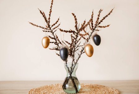 Photo for Tree branches in vase with colored Easter eggs hanging on string. Nice warm beige earthly tones. Minimal home Easter decoration. - Royalty Free Image