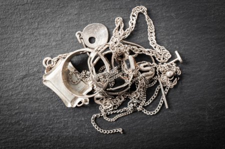 Pile de vieux bijoux en matériaux argentés, bagues, pendentifs, colliers chaîne, boucles d'oreilles. Scrap objets argentés recycler concept.