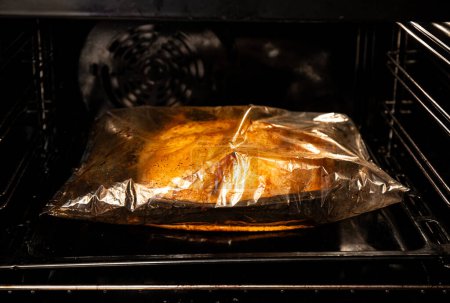 Cooking whole chicken inside cooking bag in oven. Tasty chicken dinner in the oven at home.