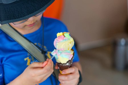 Junge mit Hut essen Eistüte mit Löffel