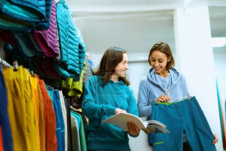 Une jeune femme explore les options vestimentaires dans une boutique avec l'aide d'un consultant compétent