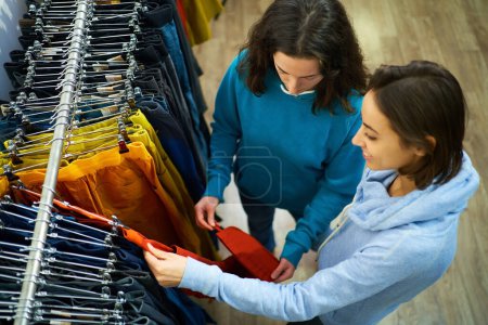 Top view femme faisant du shopping dans un magasin de vêtements, tandis qu'un consultant utile la guide à travers les dernières tendances et styles
