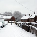 Street view fresh of snow with cars houses fences