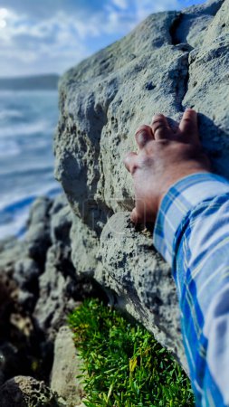 Photo for Detail of a hand clinging to a rock on a cliff with selective focus - Royalty Free Image