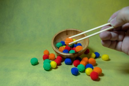 Photo for Using chopsticks to select colorful balls from a bowl, emphasizing decision-making and choice - Royalty Free Image