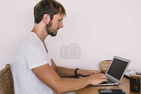 Photo for Side view of serious male software developer updating antivirus application on modern laptop computer connecting to wifi internet for online remote working,Caucasian freelancer concentrated on article - Royalty Free Image