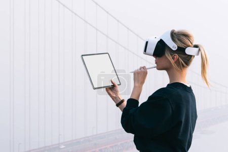 Foto de Thoughtful caucasian female work on modern touch pad wearing virtual reality glasses while planning 3D engineering construction in headset. Arquitectura aumentada con alta tecnología innovadora VR - Imagen libre de derechos