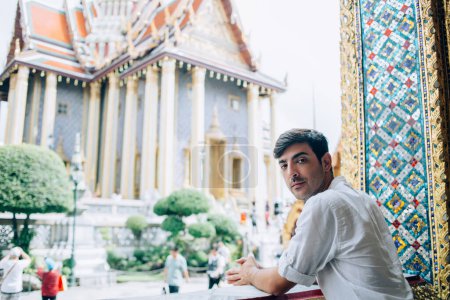 Photo for Portrait of handsome spansh guy traveler in casual wear standing near ancient architecture in Thai during his journey, young male tourist exploring asian religious - Royalty Free Image