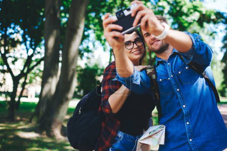 Photo for Cheerful happy couple in love in casual wear posing for making photo on camera during vacation trip in city, young hipster marriage taking selfie visiting town and sightseeing together on vacation - Royalty Free Image