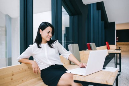 Photo for Smiling millennial 20s businesswoman in formal wear watching video online on laptop computer, positive caucasian concentrated female manager read news from exchange satisfied with finance income - Royalty Free Image