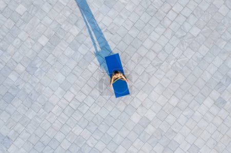 Photo for Drone view of still quiet flexible person comfortably sitting on blue yoga mat in lotus pose and recreating in daylight - Royalty Free Image