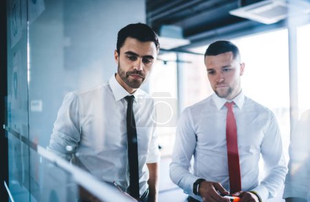 Kaukasische männliche Mitarbeiter haben Brainstorming-Kollaboration zur Kommunikation über Strategiemarketing, selbstbewusste Bürokollegen suchen Lösungen während des Arbeitsprozesses im Unternehmen