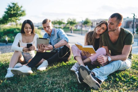 Photo for Group of millennial students enjoying gathering bonding during free time for discussing planning organisation, Caucasian users connecting to bluetooth for sharing media via smartphone and touch pad - Royalty Free Image