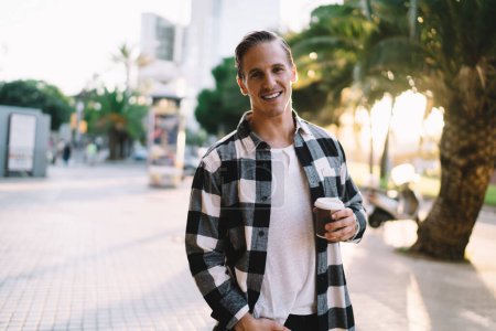 Photo for Half length portrait of smiling young man 20s in trendy wear holding coffee cup standing on city square urban setting, cheerful handsome caucasian male tourist satisfied with leisure in downtown - Royalty Free Image