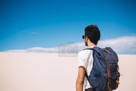 Voyageur masculin debout sous les rayons du soleil de chauffage pendant le voyage vers le parc national de sable blanc, gars errent debout à l'extérieur avec une vue imprenable sur le désert et l'horizon du ciel sur les terres arides inhabitées
