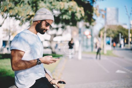 Türkische männliche Touristen auf der Suche nach Reiseinformationen für Urlaube mit 4g Internetverbindung, Hipster aus dem Nahen Osten mit Sonnenbrille und modischem Hut, die Medientexte lesen