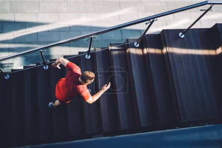 Foto de Desde arriba de cuerpo completo jogger masculino irreconocible corriendo arriba y estirando las piernas mientras hace ejercicios matutinos durante las vacaciones de verano - Imagen libre de derechos