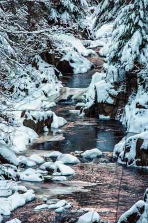 River Pattack in den schottischen Highlands, mit schneebedeckten Felsen und Bäumen auf beiden Seiten