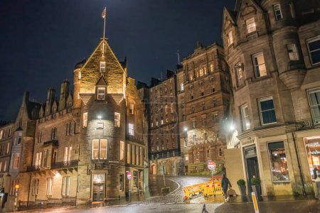 Edificios antiguos iluminados por la noche en la esquina de Market Street y Cockburn Street en el centro de Edimburgo, Escocia