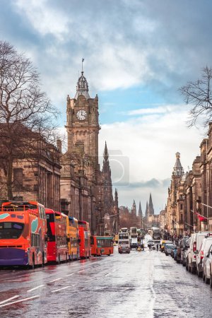 Touristenbusse parken entlang der Princes Street in Edinburgh, Schottland, mit dem Uhrenturm des Balmoral Hotels